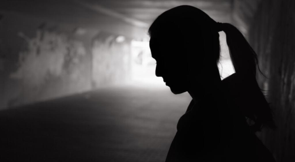 a dark silhouette of a woman with a ponytail in an alley.
