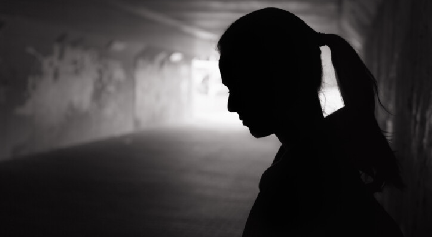 a dark silhouette of a woman with a ponytail in an alley.