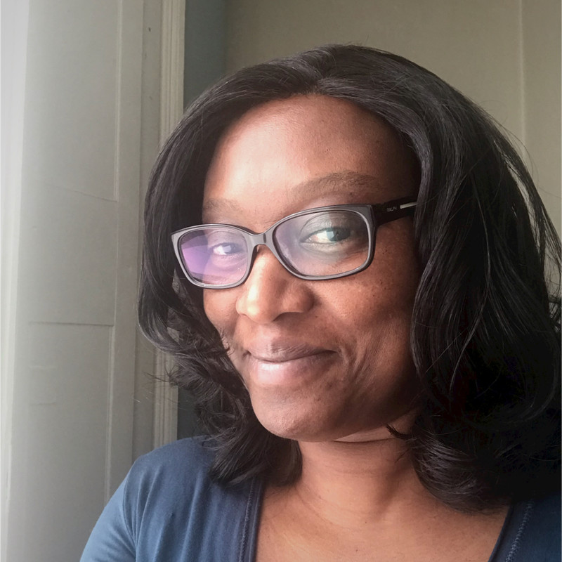 A Woman with black and black glasses smiles at the camera.
